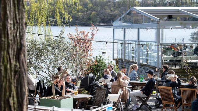 People sit in the spring sun at an outdoor restaurant in Stockholm, Sweden. Picture: AFP