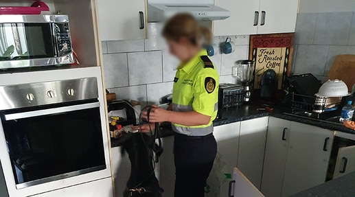 An Australian Border Force officer searches through a man's kitchen in September 2020 where he allegedly ran a national mail order drug distribution network. Picture: ABF