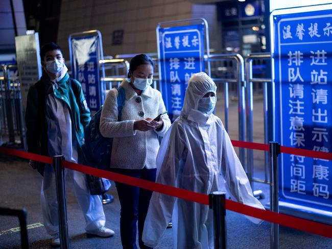 Passengers wear hazmat suit as they arrive at the Wuhan Wuchang Railway Station in Wuhan. Picture: AFP