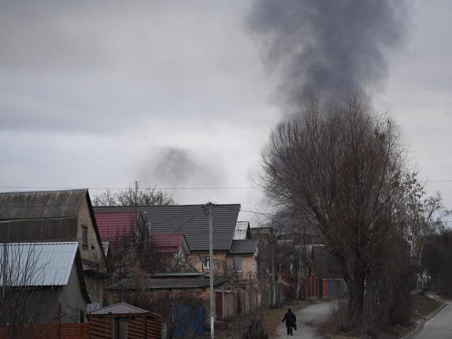 A local resident walks in a street as smoke rises near the town of Hostomel and the Antonov Airport, in northwest Kyiv. Picture: Daniel Leal/AFP