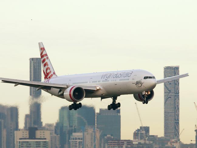 Virgin Australia plane landing at Brisbane Airport with Brisbane City buildings in background. Photographer: Liam Kidston.