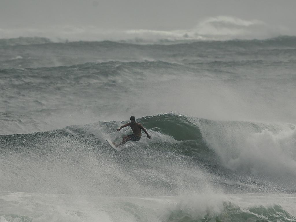 A man spotted surfing as a large a swell hits Australia’s east coast. Picture: NewsWire / Glenn Campbell