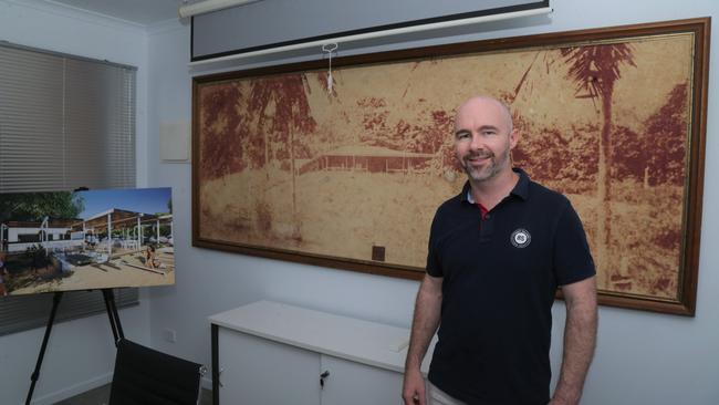 Mayfair 101 managing director James Mawhinney in front of an image of Dunk Island pioneer Ted Banfield's homestead at the firm's Mission Beach office. Picture: Peter Carruthers