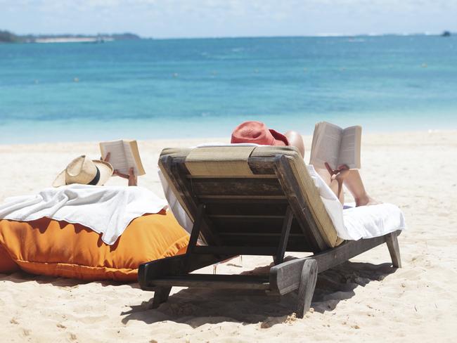 couple of people reading while sunbathing on the beach of mauritius