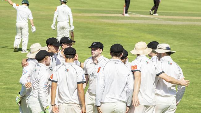 Jason Hughes huddles with teammates after lunch as David Warner walks to the crease. Pic Jenny Evans.