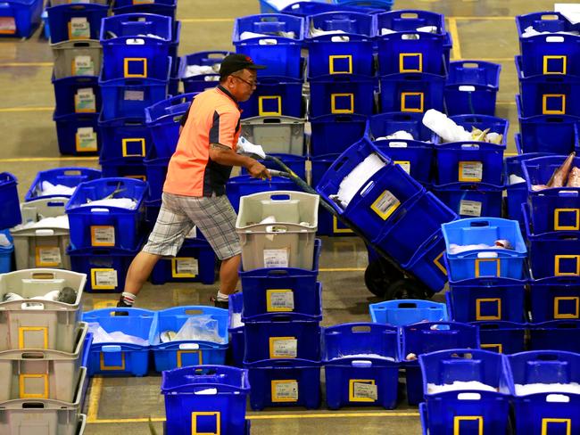 A worker uses a trolley to shift tubs of fresh fish at a Sydney Fish Markets auction. Picture Cameron Richardson