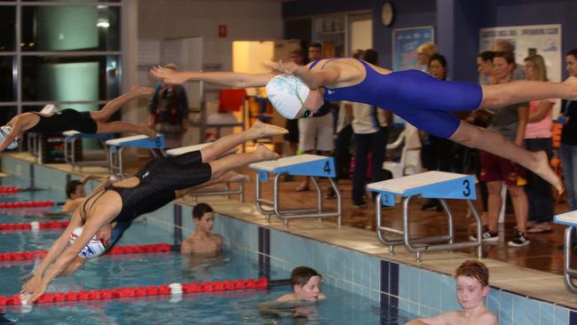 Swimmers dive in at the meet on Friday night.