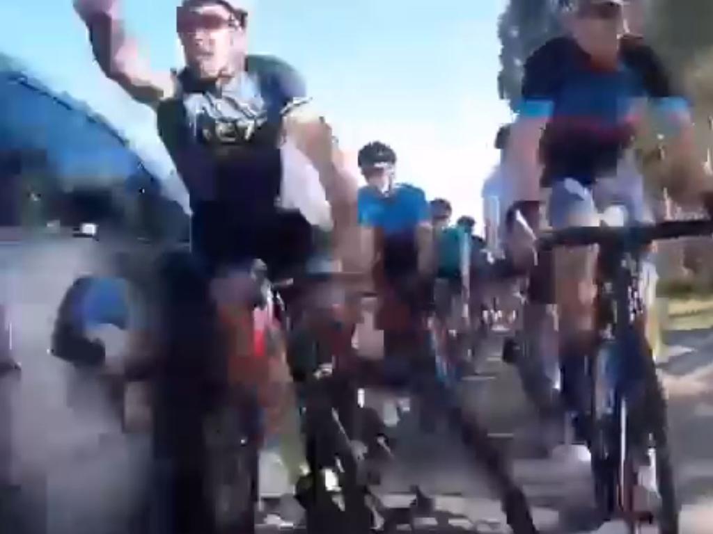 Several cars safely pass the peloton before one collides a cyclist.