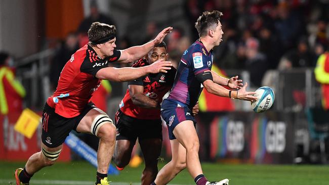 Reds fullback Jock Campbell passes the ball as Crusaders pair Scott Barrett (left) and Sevu Reece attempt to tackle him. Picture: Sanka Vidanagama / AFP