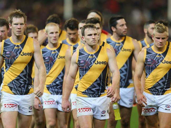 Nathan Foley leads a despondent Richmond off the field after losing to Essendon.