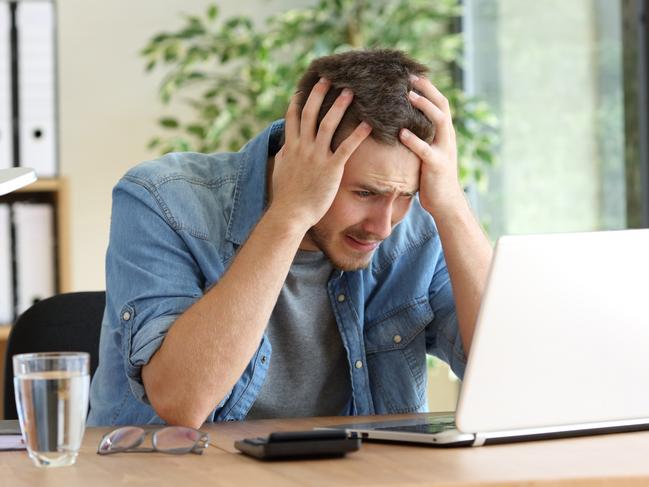 A stressed man at his computer after just realising he has been scammed. Picture: iStock.