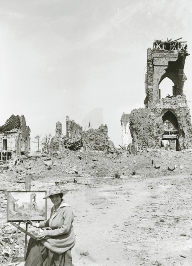 Australian artist Evelyn Chapman sits with her easel in the ruins of Villers-Brettoneaux, France. Picture: Courtesy of S.H. Ervin Gallery