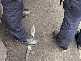 Police officers guard a machete used in a street crime. Picture: Supplied