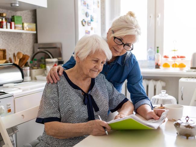 Mature woman helping elderly mother with paperwork