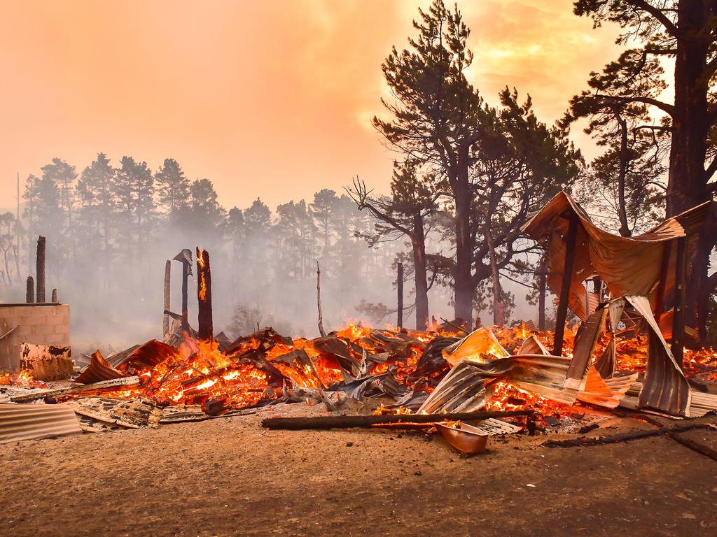 An out of control fire ripped through the Blue Mountains this afternoon. Unknown houses and other property has been destroyed along Bells Line of Road from Bilpin to Mount Tomah and further west. The remains of a house along Bells Line of Rd at Bilpin. Firefighters battle to protect property in the background. Picture: Matrix