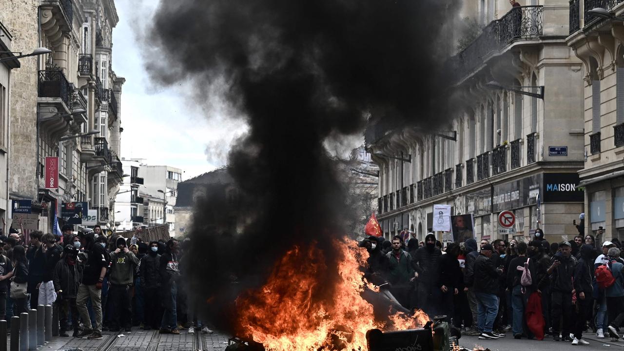 People stand behind a fire during a demonstration, a week after the government pushed a pensions reform through parliament without a vote. (Photo by Philippe LOPEZ / AFP)