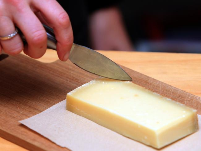 Cutting a piece of Gruyere.