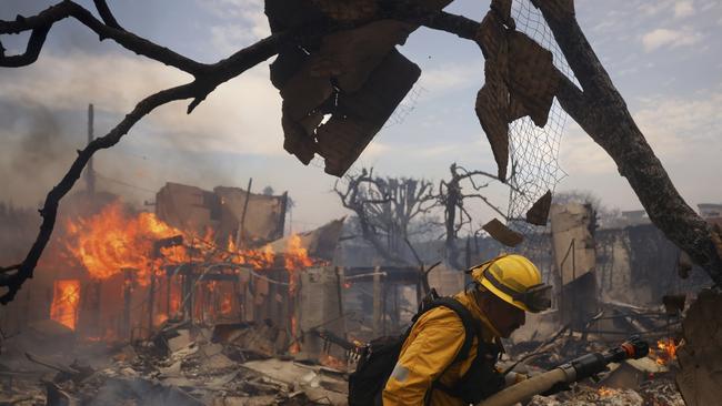 A firefighter battles the Palisades Fire around a burned structure. Picture: AP