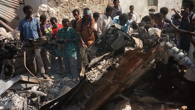 Somalis look at the wreckage of a US helicopter, in a Mogadishu street after it was shot down on October 4, 1993. Twelve soldiers were killed, 76 wounded and six others reported missing, during a battle with followers of war lord Mohamed Farah Aidid. Picture: AFP