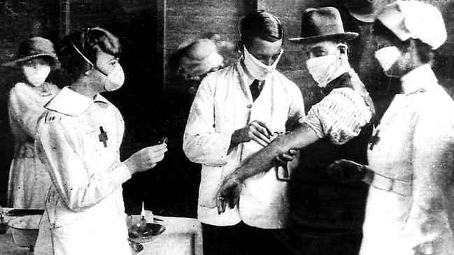 Nurses and doctors wearing protective masks vaccinate patients from Spanish flu during the 1919 epidemic