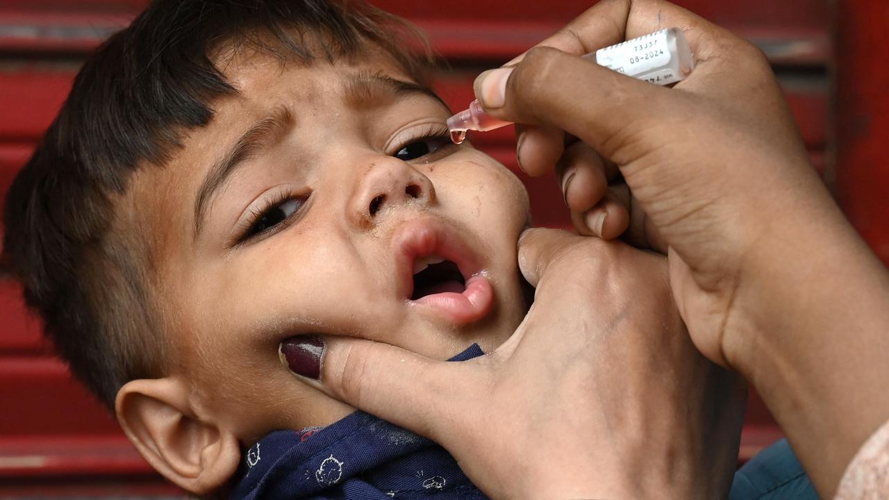 A health worker administers polio vaccine drops to a child during a polio vaccination door-to-door campaign in LahoreÂ on August 16, 2020. (Photo by Arif ALI / AFP)