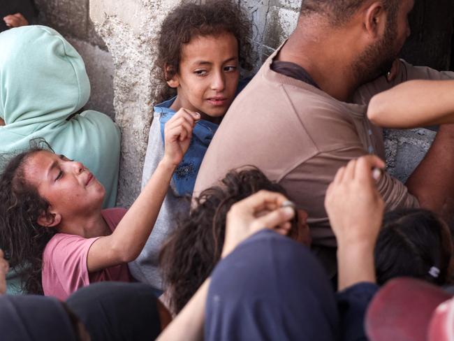 A girl reacts as she tries to hand over money to a man to buy bread while queueing in a crowd outside a bakery in Khan Yunis in the southern Gaza Strip. Picture: AFP