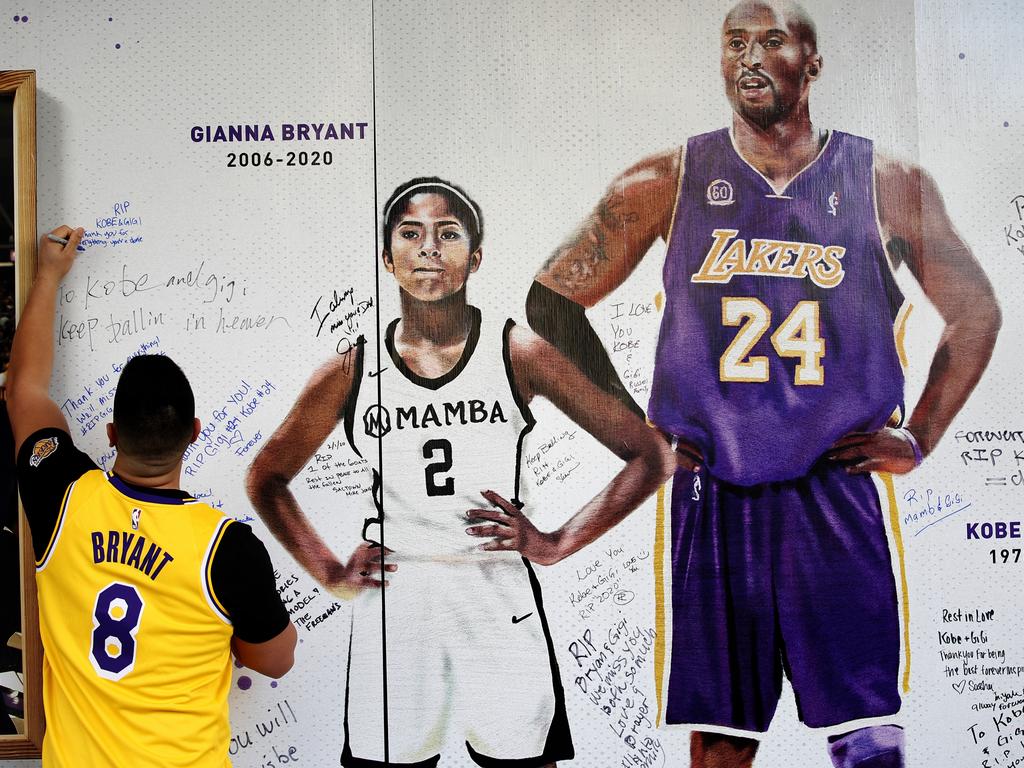 Jesse Reyes Zaragoza writes a message on a memorial display of Kobe Bryant and his daughter, Gianna. Picture: AP