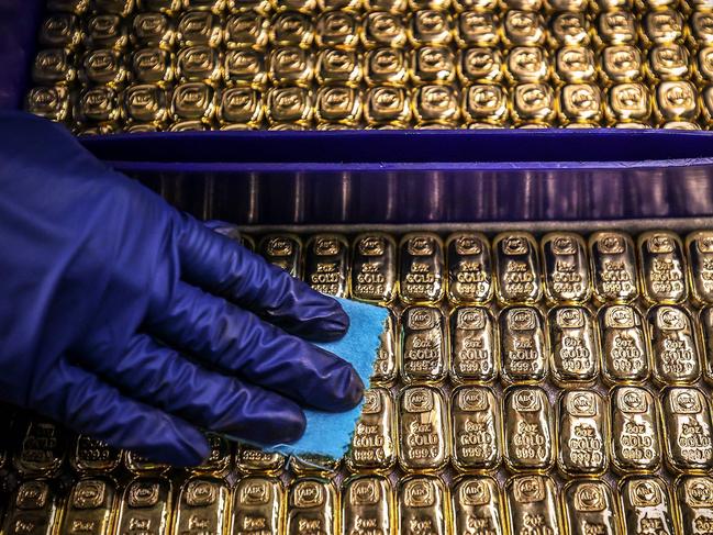 (FILES) A worker polishes gold bullion bars at the ABC Refinery in Sydney on August 5, 2020. Gold prices soared to a record high above USD 2,100 on December 4, 2023 as traders grow increasingly confident the Federal Reserve will cut interest rates in the new year. (Photo by DAVID GRAY / AFP)