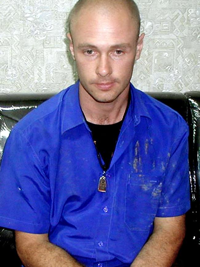 Jason Daron Mizner sits with handcuffs while waiting for an interrogation at Chiang Mai police station.