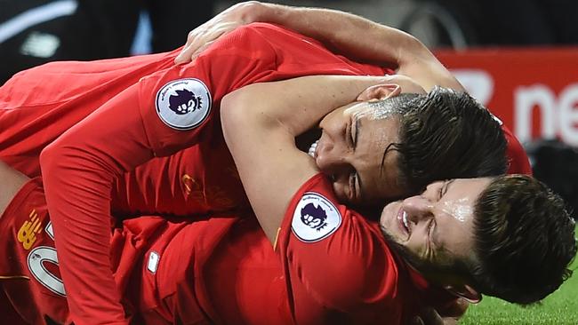 Liverpool's Brazilian midfielder Roberto Firmino (top) celebrates on the floor with Liverpool's English midfielder Adam Lallana (bottom).