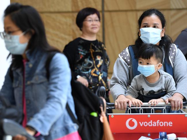 Passengers wearing protective masks arrive at Sydney International Airport in Sydney. Australia is working to keep out the deadly coronavirus, as a flight from the city at the centre of the outbreak arrives in Sydney. Picture: AAP