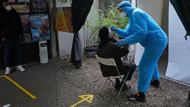 A medical worker dressed in PPE takes a throat swab from a man seeking a rapid antigen COVID test on Friday at a testing station set up on the grounds of the KitKat Club during the second wave of the coronavirus pandemic in Berlin. Picture: Getty Images