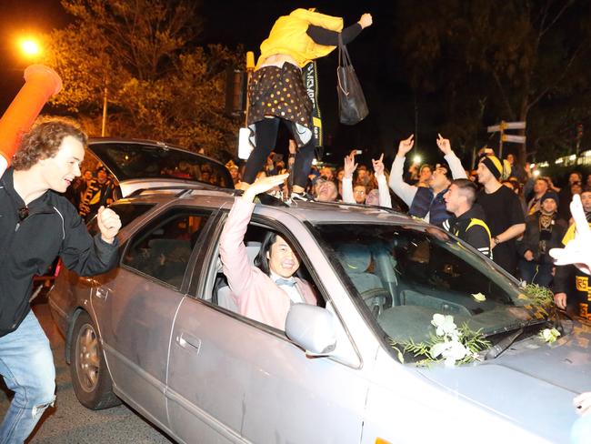 A driver is not fazed as a supporter jumps on his roof in Swan St. Picture: Patrick Herve