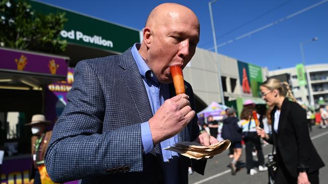 Opposition Leader Peter Dutton eats a dagwood dog as he visits the Ekka show at the RNA Showgrounds. Picture: NCA NewsWire / Dan Peled