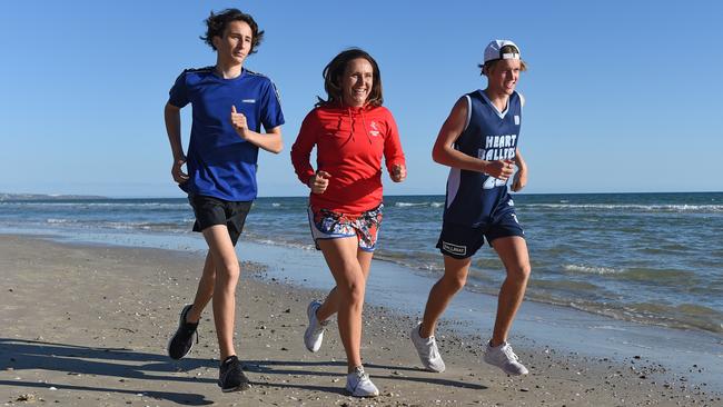 Marathon runner and fitness coach Anna Liptak, who is recovering from COVID-19 training for this year's City-Bay with her sons Lachy Shinnick, 14 and Zach Shinnick, 16, at Glenelg. Picture: Naomi Jellicoe