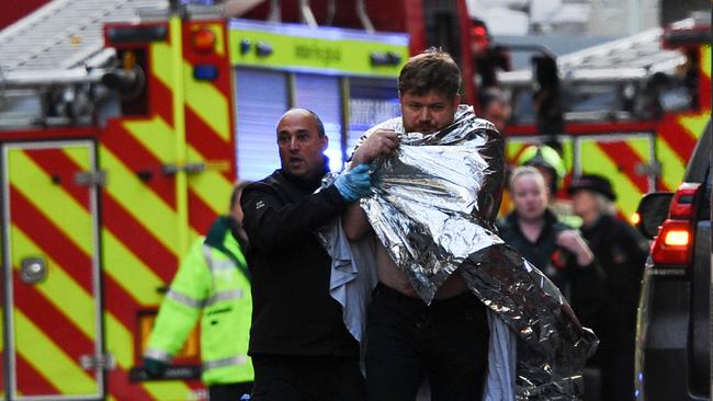 Police assist an injured man near London Bridge. Picture: AFP