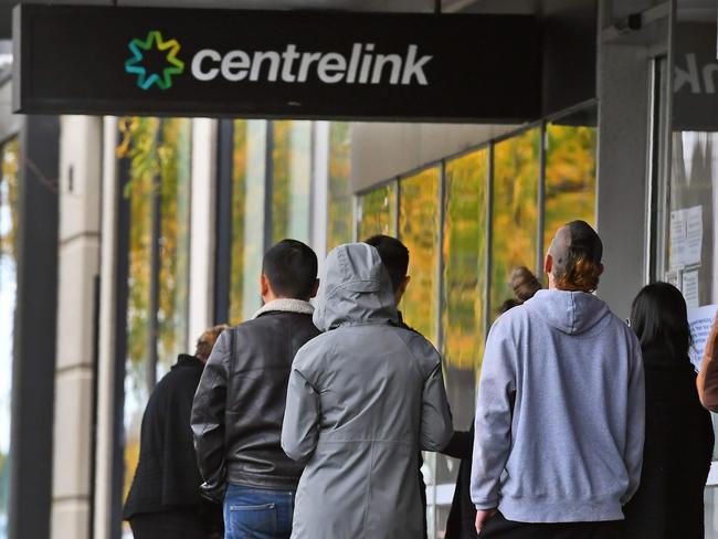 People queue up outside a Centrelink office in Melbourne on April 20, 2020, which delivers a range of government payments and services for retirees, the unemployed, families, carers and parents amongst others. - A report from the Grattan Institute predicts between 14 and 26 per cent of Australian workers could be out of work as a direct result of the coronavirus shutdown, and the crisis will have an enduring impact on jobs and the economy for years to come. (Photo by William WEST / AFP)