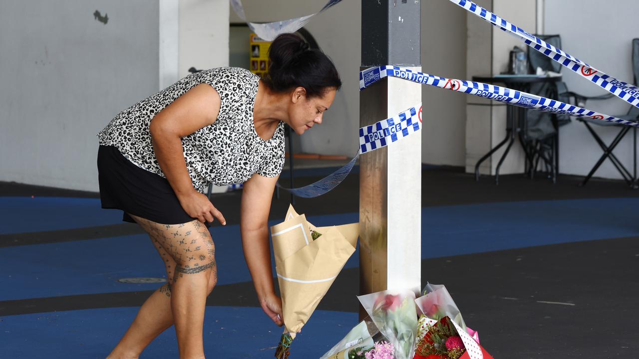 A woman places flowers at the scene at Town Square Shopping Centre stabbing. Picture Lachie Millard