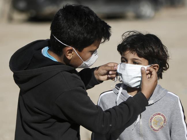 A boy adjusts the protective mask of another in a street outside their homes in Gaza City. Picture: AFP