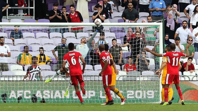 Socceroos goalkeeper Mat Ryan makes a fingertip save from a fierce free kick by Jordan’s Baha Abdelrahman last night. Picture: AFP