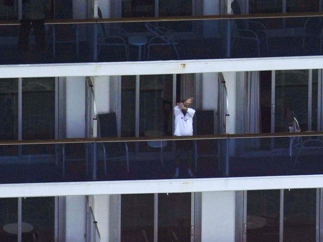 A passenger waves from the cruise ship Diamond Princess anchored off Yokosuka, near Tokyo.