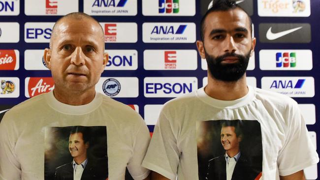 (L-R) Syria's head coach Fajr Ibrahim and player Osama Omari (R) wear T-shirts with a portrait of dictator Bashar al-Assad in 2015.