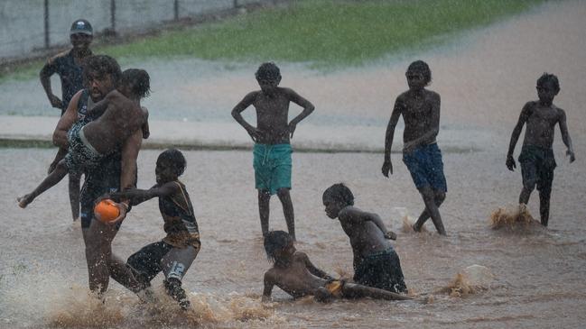 Tiwi Bombers player and teacher on the island Tanna Blackney-Noter playing a game with school kids in the wet. Picture: Jack Riddiford / AFLNT Media