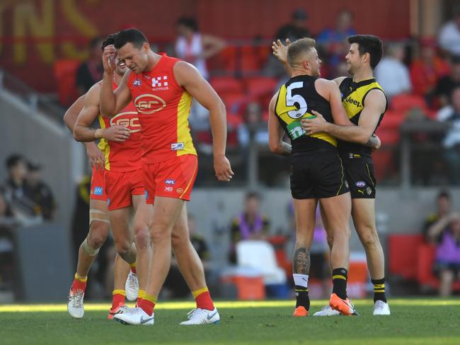 Brandon Ellis of the Tigers (second right) celebrates with teammate Trent Cotchin after kicking a goal as Steven May (left) of the Suns reacts during the Round 21 AFL match between the Gold Coast Suns and the Richmond Tigers at Metricon Stadium on the Gold Coast, Saturday, August 11, 2018. Picture: AAP Image/Darren England