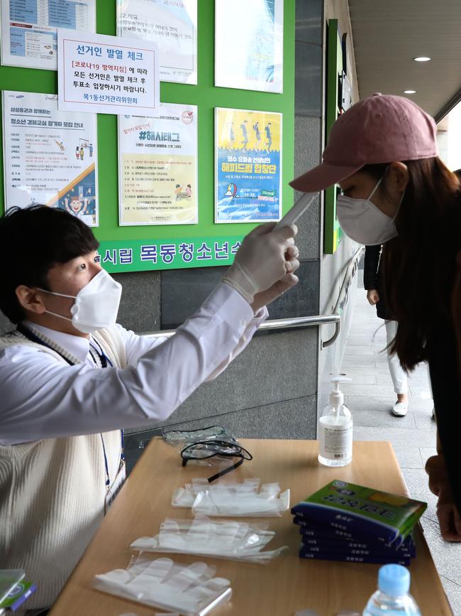 A South Korean woman wears plastic gloves has her temperature checked upon his arrival to cast her vote. Picture: Getty Images