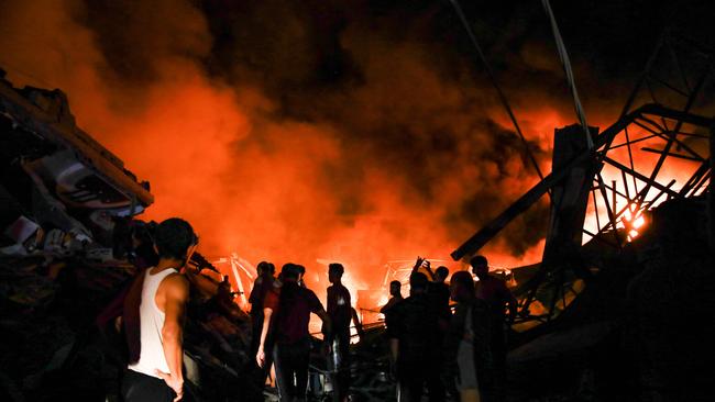 Smoke and fire rise from buildings as people gather amid the destruction in the aftermath of an Israeli strike on Gaza City on October 26. Picture: AFP