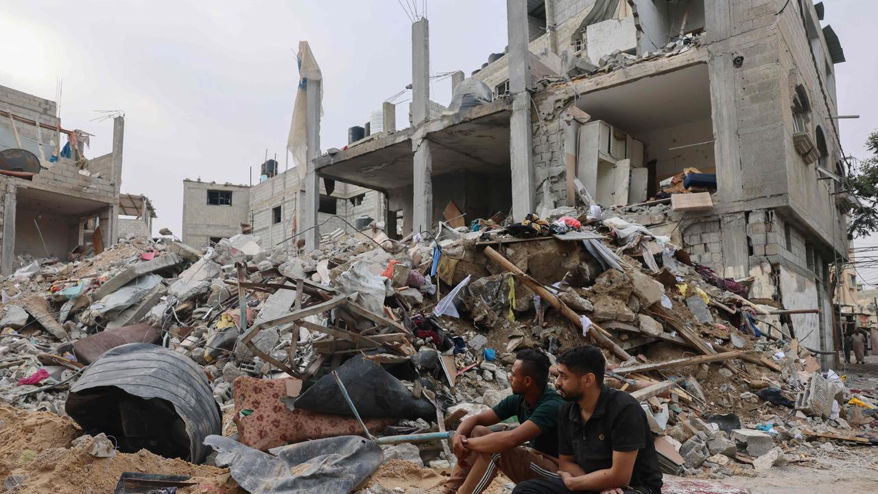 Two young Palestinians sit in front of a levelled building following overnight Israeli air strike on Rafah in the southern Gaza Strip. Picture: AFP