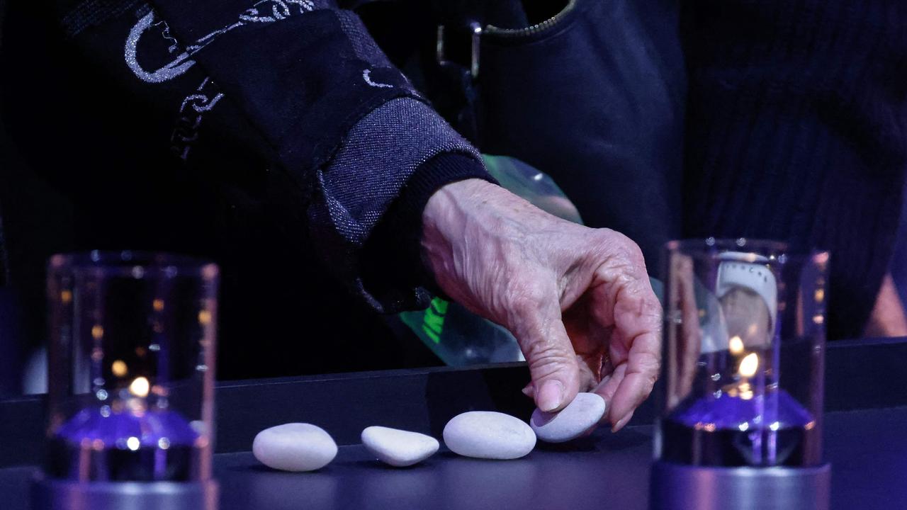 A Holocaust survivor placed stones between candles during commemorations on the 80th anniversary of the liberation of the German Nazi concentration camp Auschwitz-Birkenau at the site in Poland on January 27. Picture: Ludovic Marin/ Pool/ AFP