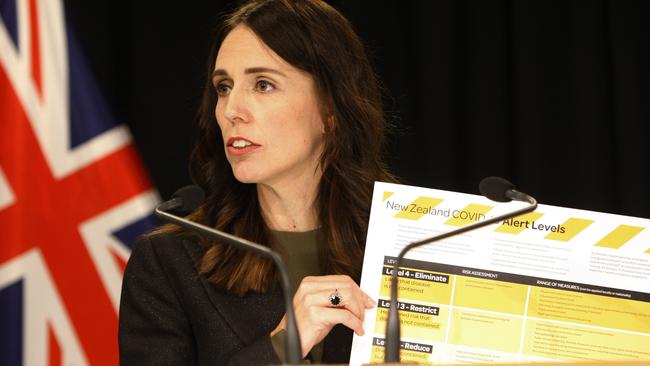 New Zealand Prime Minister Jacinda Ardern holds up a card showing a new alert system for COVID-19. Picture: AFP.