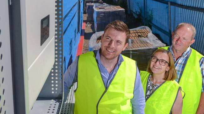 Stoddart Group general manager Adam Taylor with homeowners Ken and Gina Carter inspect the batteries and inverter recessed into the wall of the new home in Athelstone. Picture: AAP/Brenton Edwards